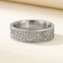 Silver ring with intricate designs on a beige background
