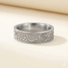 Silver ring with intricate designs on a beige background
